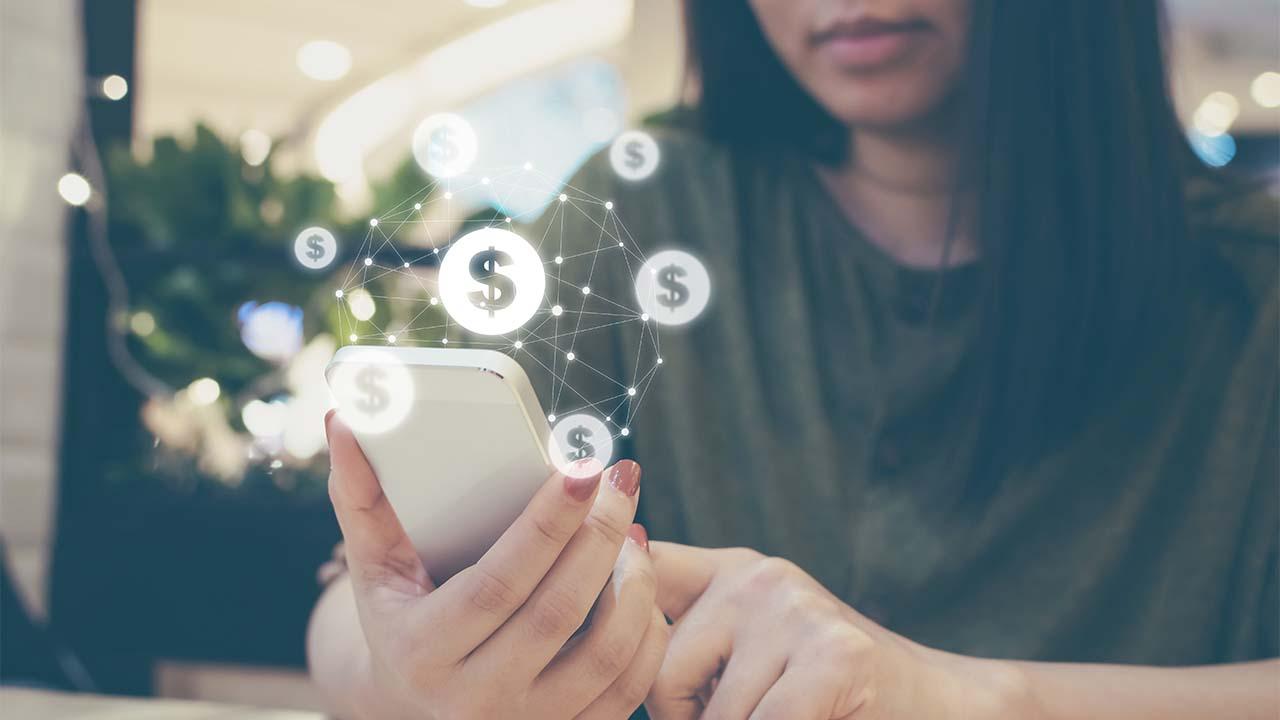 Mulher segura celular com cifrões em volta, mostrando que a portabilidade de operadoras de celular pode ajudar a economizar