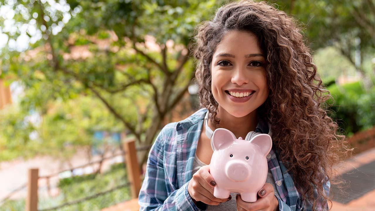 Na foto, jovem com cofrinho, trazendo a ideia de “Comece o ano bem informado para investir'